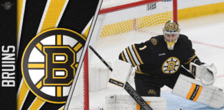 Jeremy Swayman in Boston Bruins uniform standing in front of a net with a determined expression.