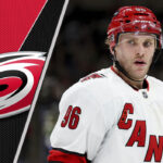 Mikko Rantanen Trade Rumors: Hurricanes Face Crucial Decision Mikko Rantanen in Hurricanes jersey, pondering trade rumors with NHL backdrop