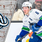 Brock Boeser in action, with the Utah Mammoth logo subtly in the background, representing NHL trade rumors.