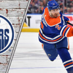 Evan Bouchard Bombshell? Why Oilers Fans Should Watch Out for Offer Sheets! Edmonton Oilers defenseman Evan Bouchard looking focused on the ice, surrounded by action, representing NHL trade rumors.
