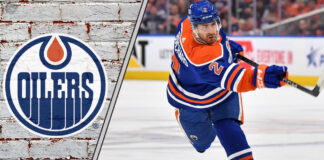 Edmonton Oilers defenseman Evan Bouchard looking focused on the ice, surrounded by action, representing NHL trade rumors.