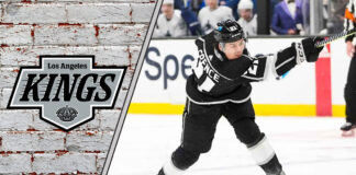 Los Angeles Kings defenseman Jordan Spence skates with the puck during an NHL game, with NHL trade rumors swirling around him.