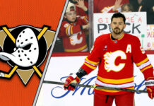 Calgary Flames defenseman MacKenzie Weegar skates with the puck during an NHL game, with a focused expression.
