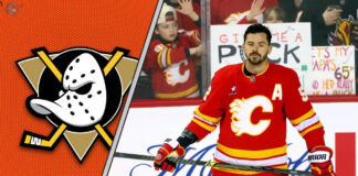Calgary Flames defenseman MacKenzie Weegar skates with the puck during an NHL game, with a focused expression.