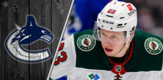 Minnesota Wild forward Marco Rossi looks on during an NHL game, with the text "Marco Rossi Rumors" overlaid.
