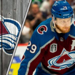 Colorado Avalanche forward Nathan MacKinnon skates with the puck, focused on the play.