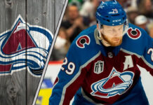 Colorado Avalanche forward Nathan MacKinnon skates with the puck, focused on the play.