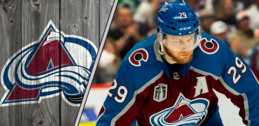 Colorado Avalanche forward Nathan MacKinnon skates with the puck, focused on the play.