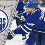 Max Pacioretty in a Leafs jersey, looking focused during a game, with the Edmonton Oilers logo superimposed in the corner.