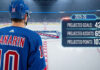 Artemi Panarin of the New York Rangers, wearing his #10 jersey, stands at center ice and looks at the team logo. A graphic overlay shows his projected 2025-26 stats: 42 goals, 65 assists, and 107 points.