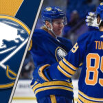 Buffalo Sabres celebrating a goal with the Sabres logo on a backdrop