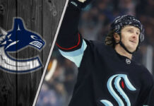 Jared McCann skates in his Seattle Kraken uniform, with the Vancouver Canucks logo faded into the background, illustrating recent NHL trade rumors.