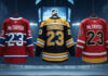 A widescreen image of three hockey jerseys hanging from the rafters of an NHL arena. The first is a Montreal Canadiens jersey, the second a Boston Bruins jersey, and the third a Calgary Flames jersey, all with the name "McTavish" and the number 23 on the back.