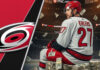 Nikolaj Ehlers in a Carolina Hurricanes jersey sitting on money at PNC Arena after signing a new contract.