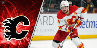 Calgary Flames defenseman Rasmus Andersson skates with the puck during an NHL game, with a focused expression.