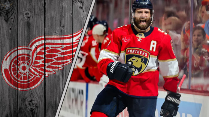 Aaron Eblad celebrating a goal in a Florida Panthers jersey with the Detroit Red Wings logo to the left