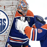 Edmonton Oilers goalies celebrating a win, with the team's logo in the background.