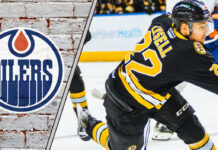 An action shot of Boston Bruins forward Fabian Lysell skating during an NHL game, with Edmonton Oilers logo to the left