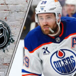 Leon Draisaitl skating with the puck with the NHL logo to his left