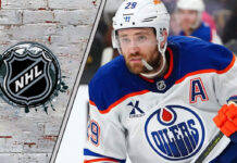 Leon Draisaitl skating with the puck with the NHL logo to his left