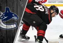 An image of Jack Roslovic in a Carolina Hurricanes jersey, with the Vancouver Canucks logo in the background.
