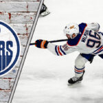 Edmonton Oilers defenseman Jake Walman shooting the puck during an NHL game.