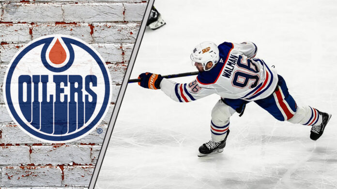 Edmonton Oilers defenseman Jake Walman shooting the puck during an NHL game.