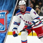 JT Miller skating with the New York Rangers logo in the background