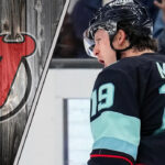Seattle Kraken forward Jaren McCann celebrating a goal during a game with the New Jersey Devils logo to the left as NHL trade rumors swirl around him