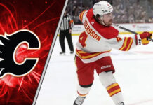 Calgary Flames defenseman Rasmus Andersson taking a shot during an NHL game, with a focus on the ongoing NHL trade rumors surrounding him