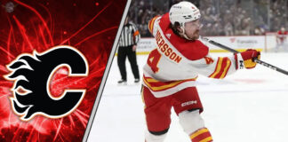 Calgary Flames defenseman Rasmus Andersson taking a shot during an NHL game, with a focus on the ongoing NHL trade rumors surrounding him