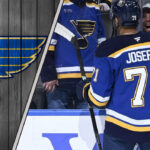 St. Louis Blues forward Mathieu Joseph talking to his teammates, symbolizing the internal competition for roster spots amidst NHL trade rumors