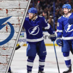 The Tampa Bay Lightning team celebrating a goal on the ice, with the crowd cheering in the background.