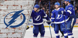 The Tampa Bay Lightning team celebrating a goal on the ice, with the crowd cheering in the background.