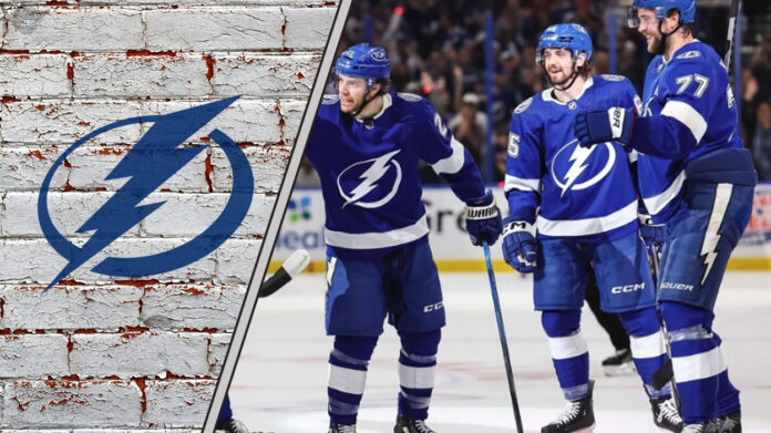 The Tampa Bay Lightning team celebrating a goal on the ice, with the crowd cheering in the background.