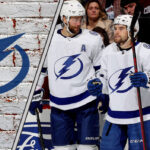 The Tampa Bay Lightning team celebrating a goal on the ice, with the crowd cheering in the background.