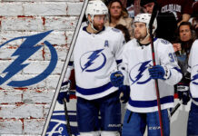 The Tampa Bay Lightning team celebrating a goal on the ice, with the crowd cheering in the background.