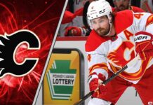 Calgary Flames defenseman Rasmus Andersson skates with the puck during an NHL game, focused on the play amidst swirling NHL trade rumors about his contract.