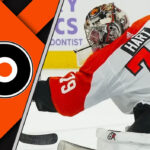 Carter Hart in a Philadelphia Flyers jersey, making a save in a packed arena.