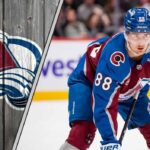 Colorado Avalanche forward Martin Necas skates with the puck during an NHL game, with the crowd blurred in the background.