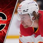 Calgary Flames forward Connor Zary skates with the puck during an NHL game, focused on the play.