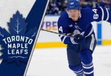An action shot of Toronto Maple Leafs forward David Kampf skating during an NHL game, with the puck on his stick.