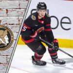 Ottawa Senators defenseman Jake Sanderson skating with the puck during an NHL game, ready to make a play.
