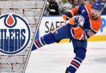 Edmonton Oilers defenseman Jake Walman skating with the puck during an NHL game.