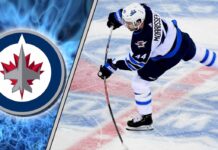 Winnipeg Jets defenseman Josh Morrissey skating with the puck during an NHL game, quarterbacking the power play.