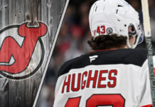 New Jersey Devils defenseman Luke Hughes skating during an NHL game, looking focused on the play.