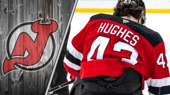 New Jersey Devils defenseman Luke Hughes skating with the puck during an NHL game, illustrating his contract negotiation stalemate with the team.