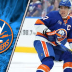 New York Islanders captain Anders Lee skating in his blue and orange jersey during an NHL game, looking focused.