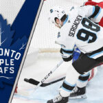 Could a Mikhail Sergachev Trade Transform the Toronto Maple Leafs’ Blue Line? Utah Mammoth defenseman Mikhail Sergachev skates with the puck during an NHL game, with the Toronto Maple Leafs logo visible in the background.