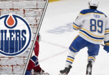 Alex Tuch skates in his Buffalo Sabres jersey during an NHL game, eyed by the Edmonton Oilers and Boston Bruins.